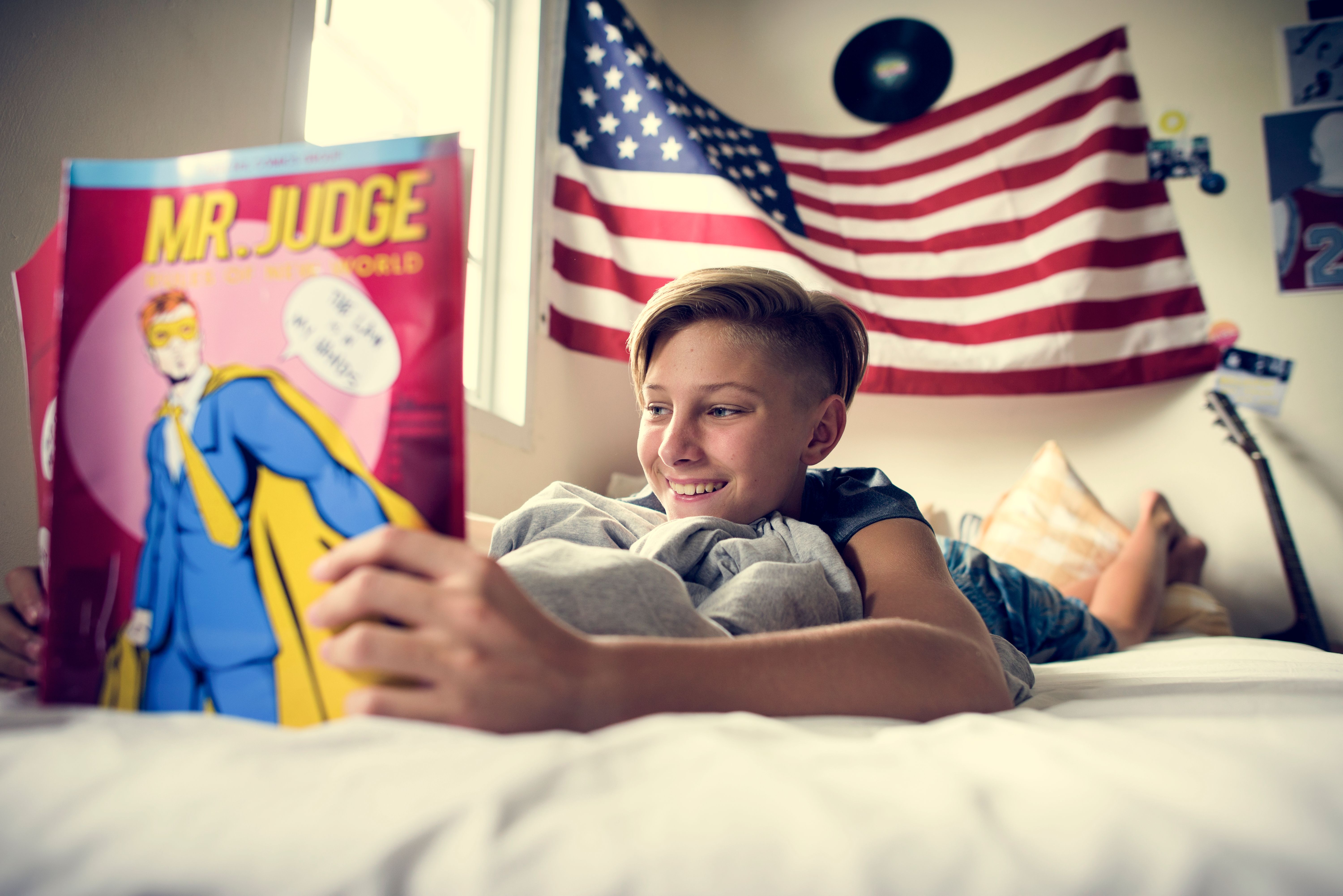 Boy lost in his comic, sprawled on the bed