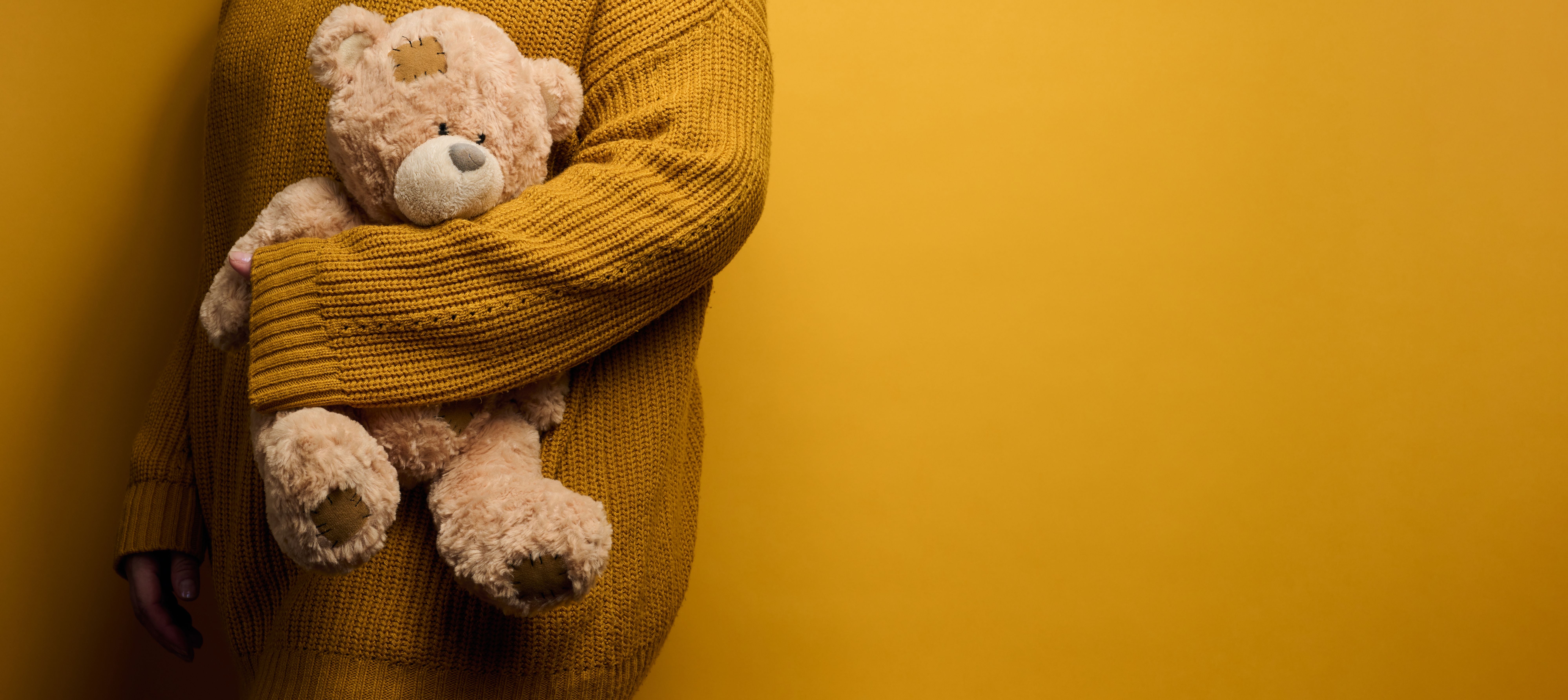 Woman in a knitted sweater hugging a worn teddy