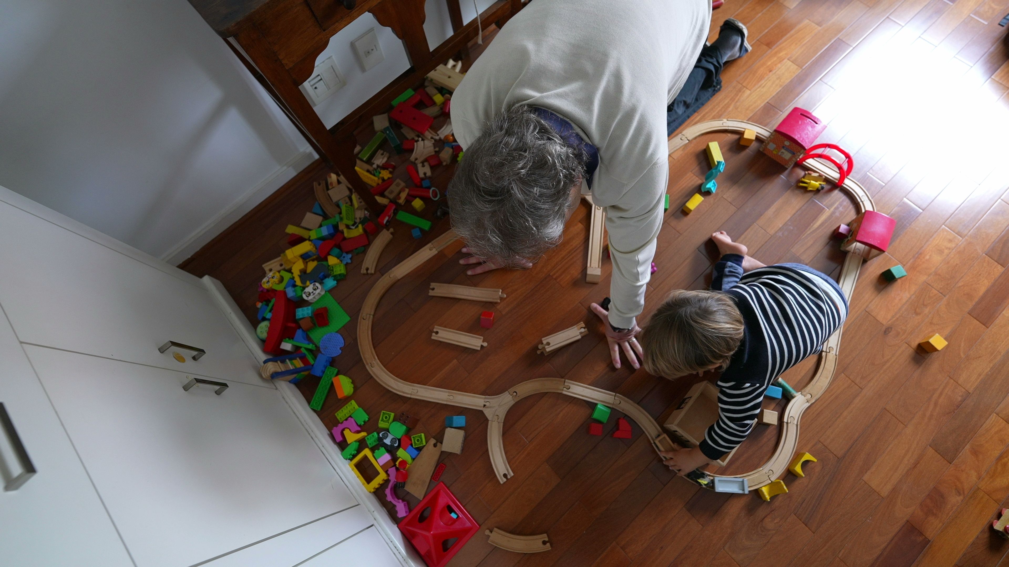 Overhead: grandpa and grandson lay vintage train tracks